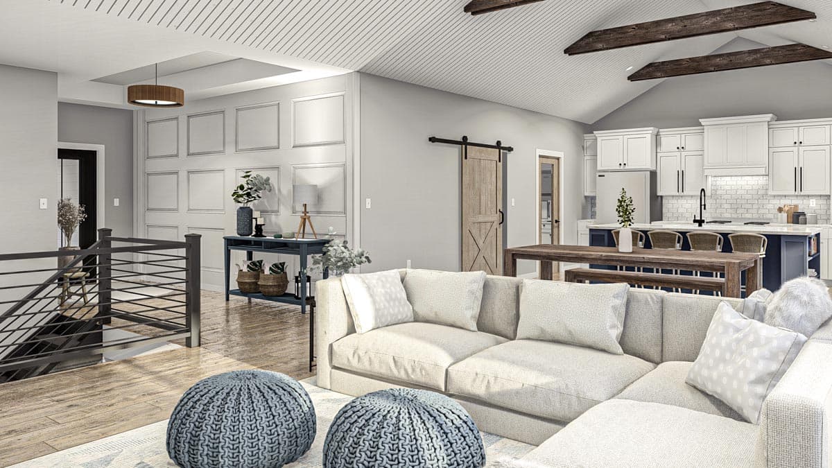 Open concept living space with vaulted ceiling, exposed beams, barn door, kitchen island with seating, and a sectional sofa.