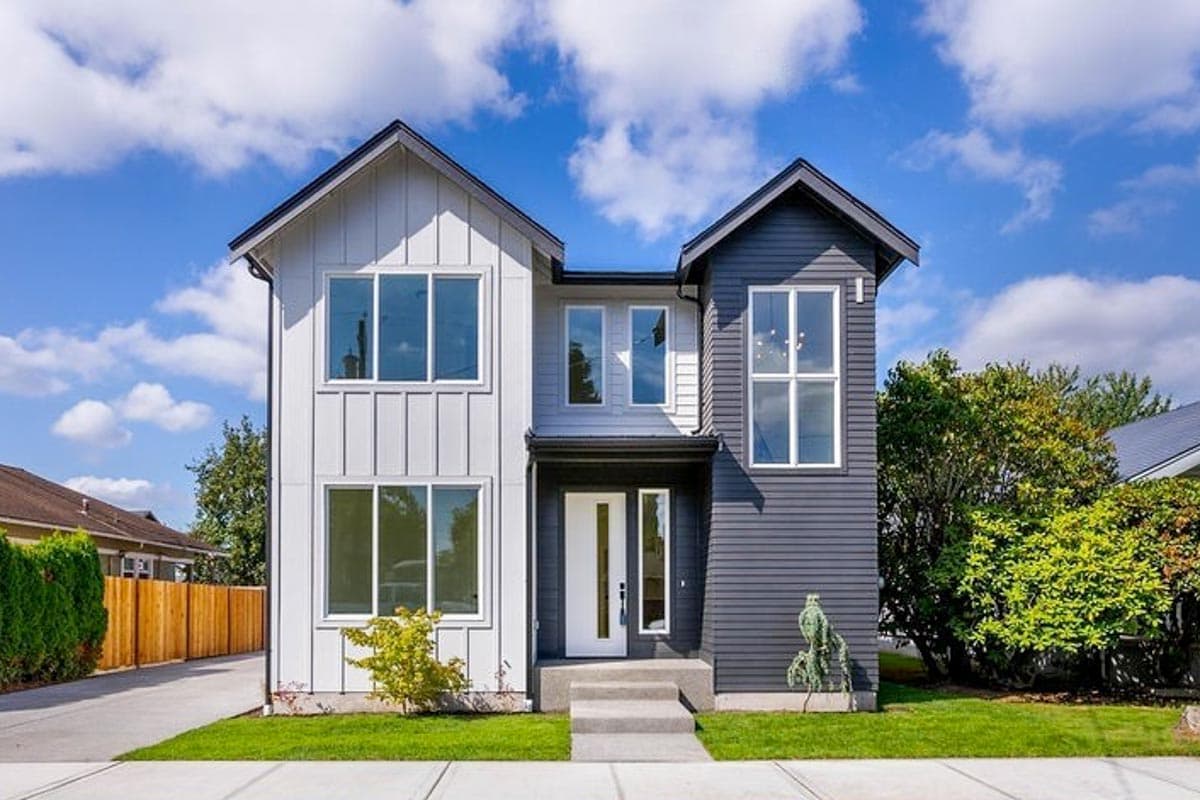 House plan exterior. Two-story Modern house with board-and-batten siding. Features include multiple gables and large, multi-pane windows.