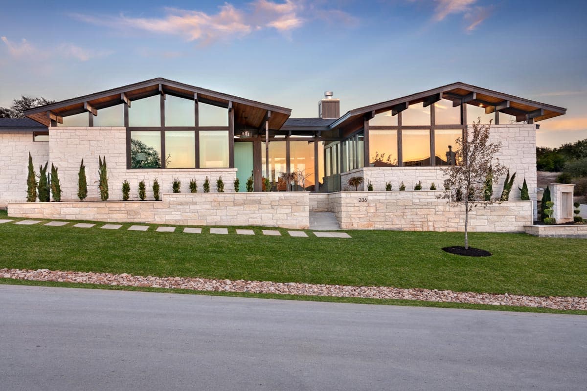 Modern house plan exterior with stone facade, asymmetrical gabled rooflines, and expansive clerestory windows.