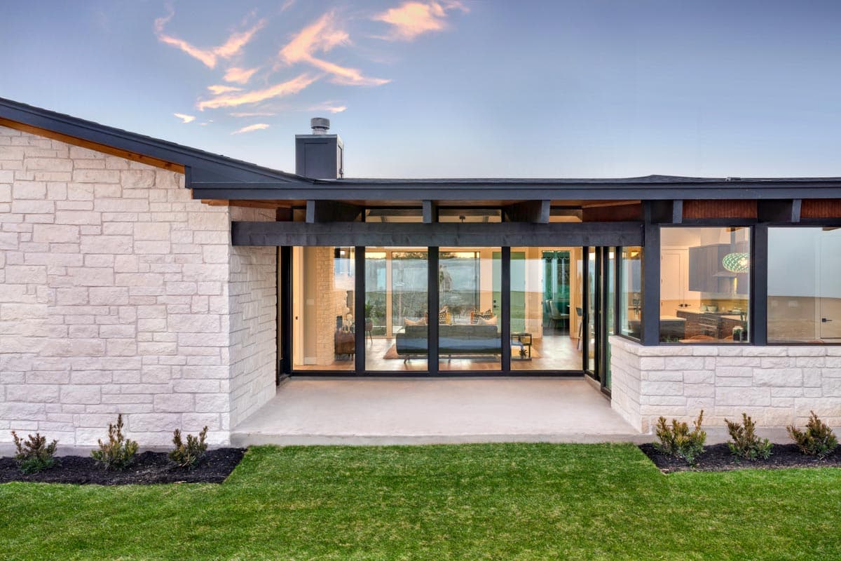 Modern ranch house plan exterior with white stone facade, flat roof, and floor-to-ceiling windows.