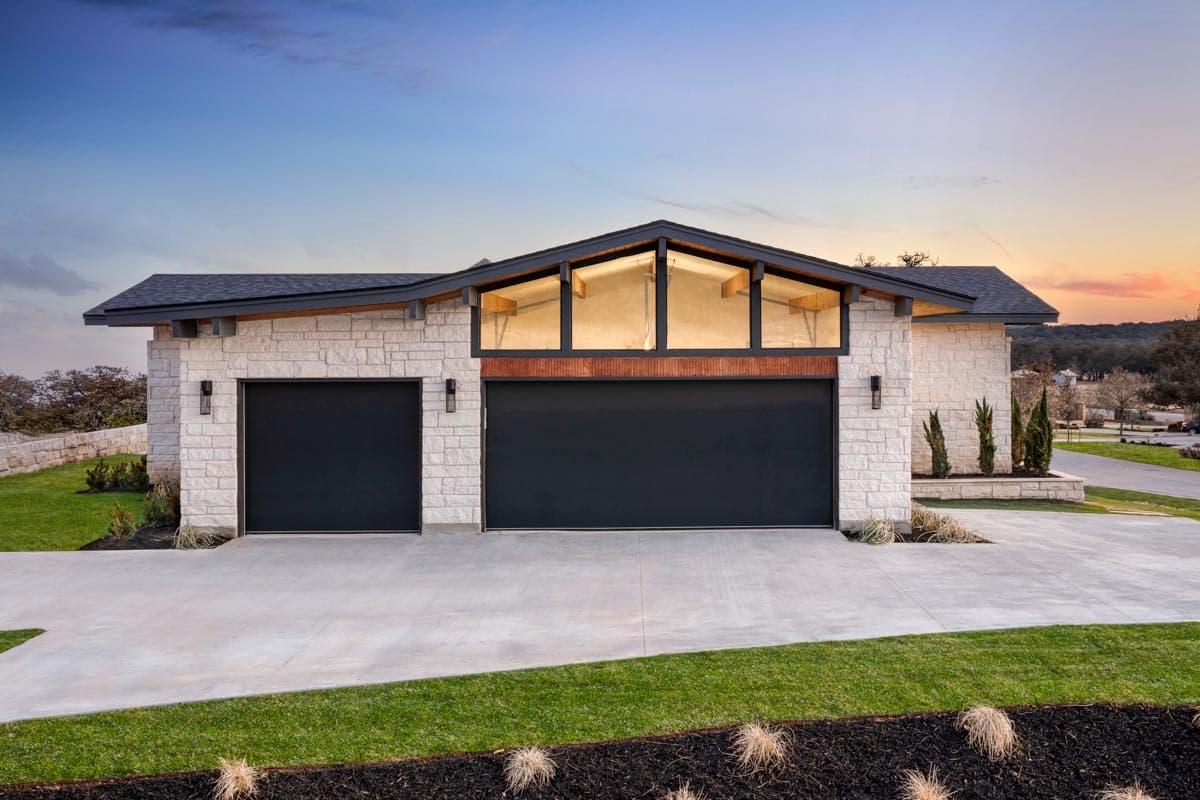 Modern house plan exterior with stone facade, two-car garage, and a central section with a gable window.