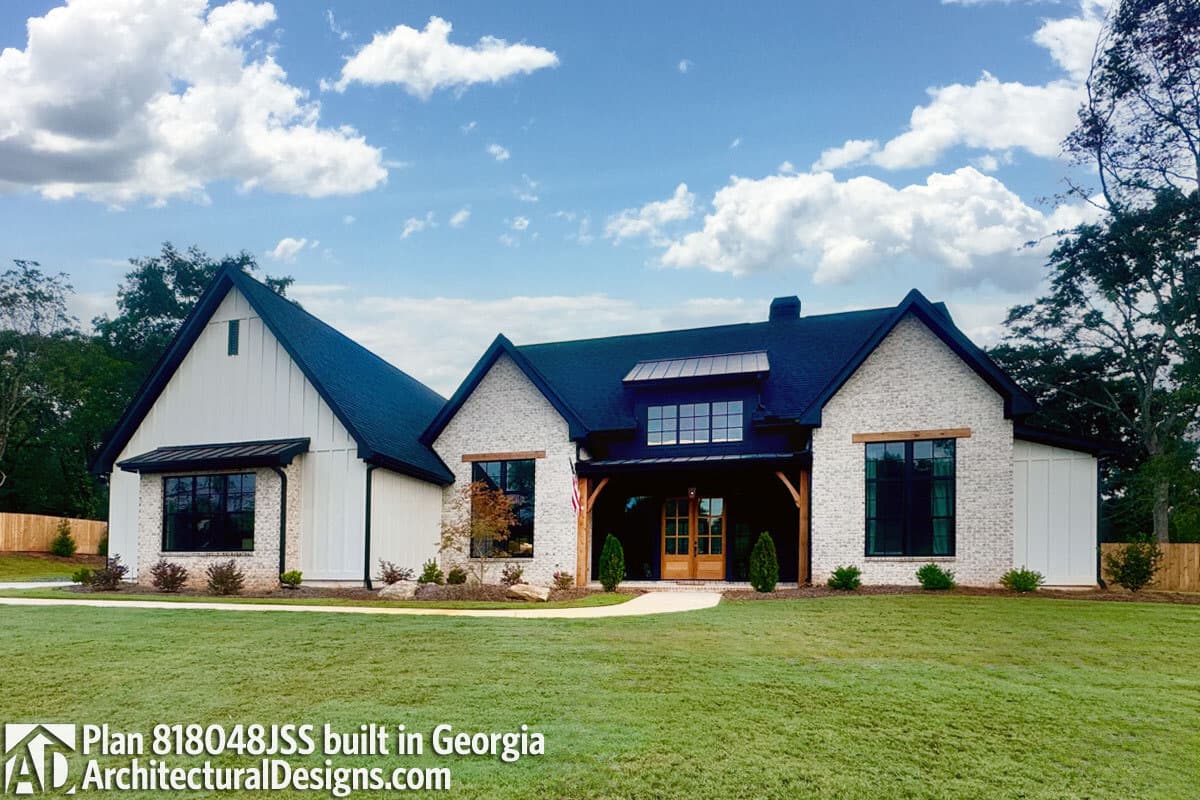 House plan exterior: Modern Farmhouse style, one-and-a-half stories, with brick and vertical siding, gables, and prominent dormer.