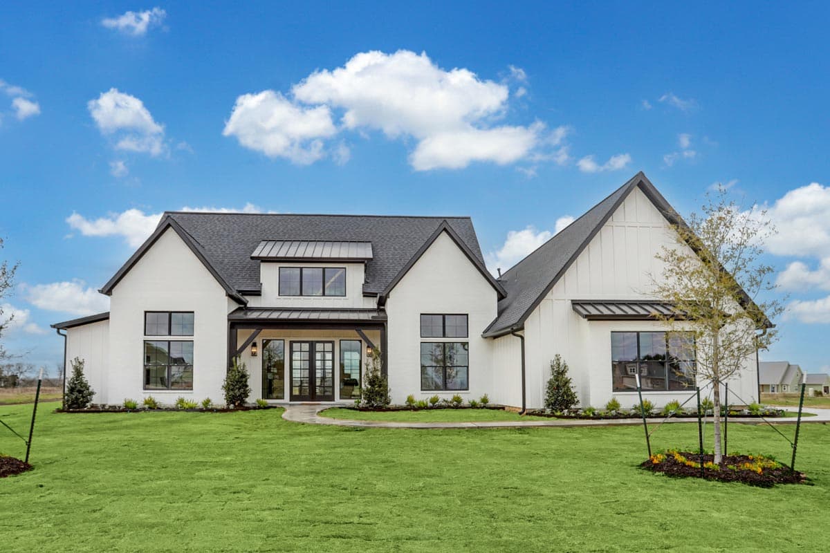House plan exterior. Two-story Modern Farmhouse with gabled rooflines, black-framed windows, and covered porch with exposed beams.