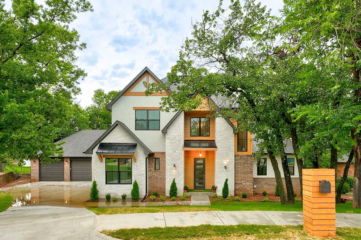 House plan exterior. Two-story Modern Farmhouse with gabled roof, brick and stone facade, and attached garage. Includes transom windows.