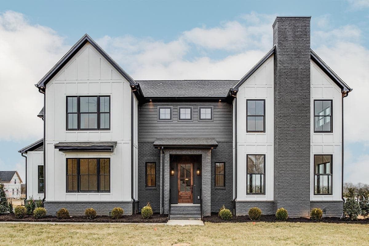 House plan exterior. Two-story Modern Farmhouse with gables, a brick chimney, and dark-framed windows. Features a covered entry.