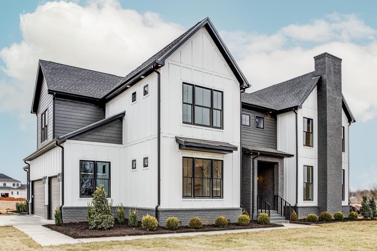 Modern Farmhouse house plan exterior with white board and batten siding, dark gray lap siding, gables, and prominent brick chimney.