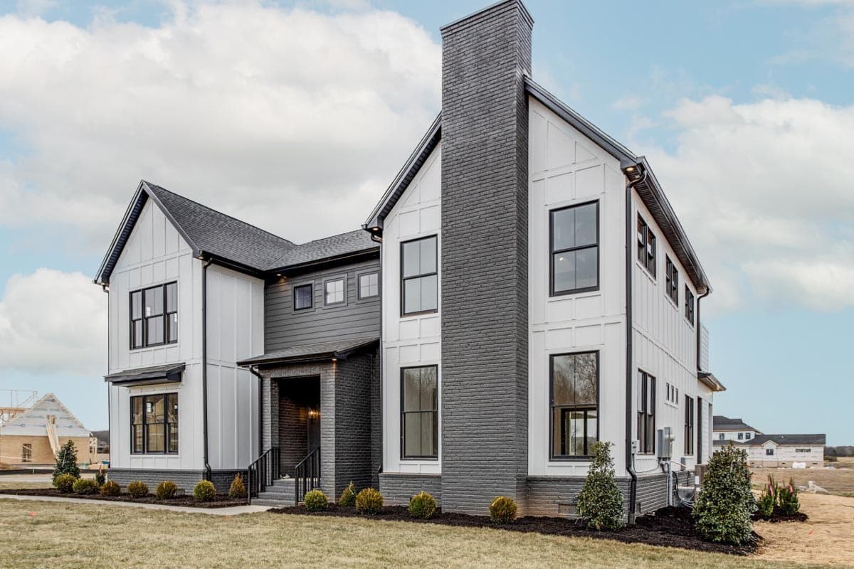 Modern Farmhouse house plan exterior with white board-and-batten siding, dark brick chimney, and gabled rooflines.