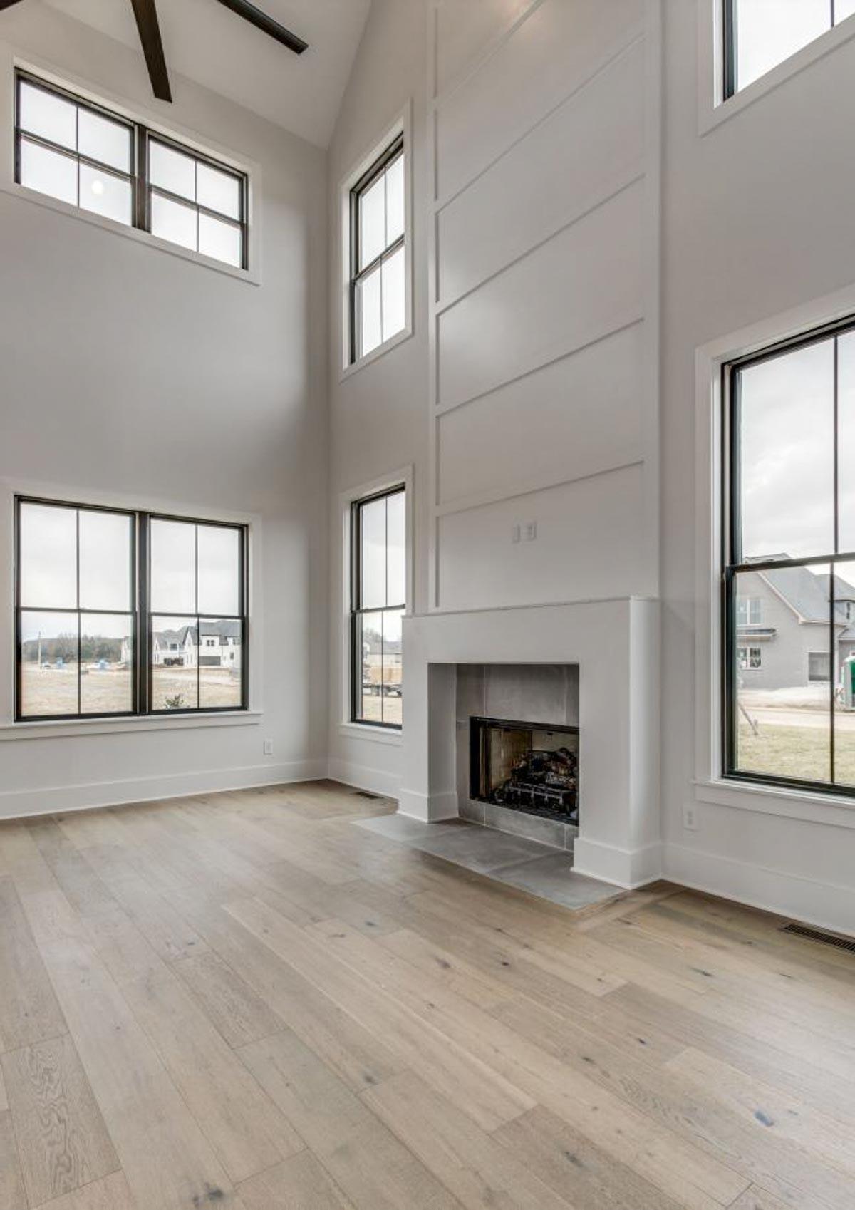 Living room with vaulted ceiling, fireplace, and large windows.