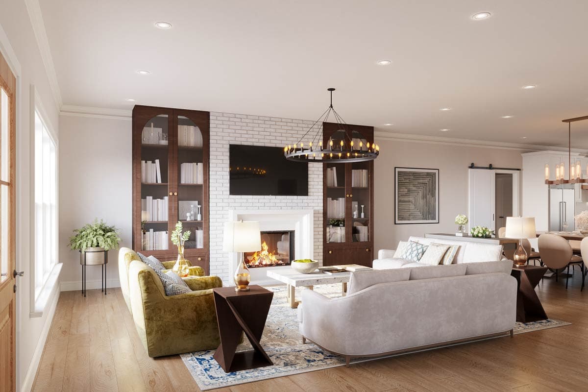 A luxurious living room with a fireplace, bookshelves, and two seating areas. A large chandelier hangs above a modern white couch and a patterned rug.