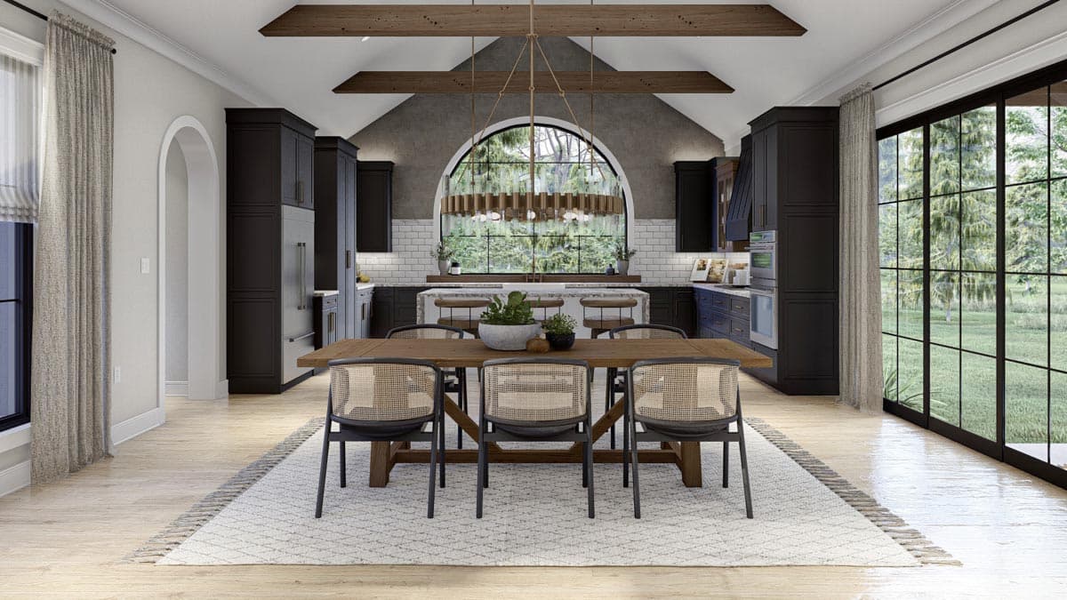 Modern kitchen with dark cabinets, island with seating, vaulted ceiling with beams, and large arched window overlooking trees.