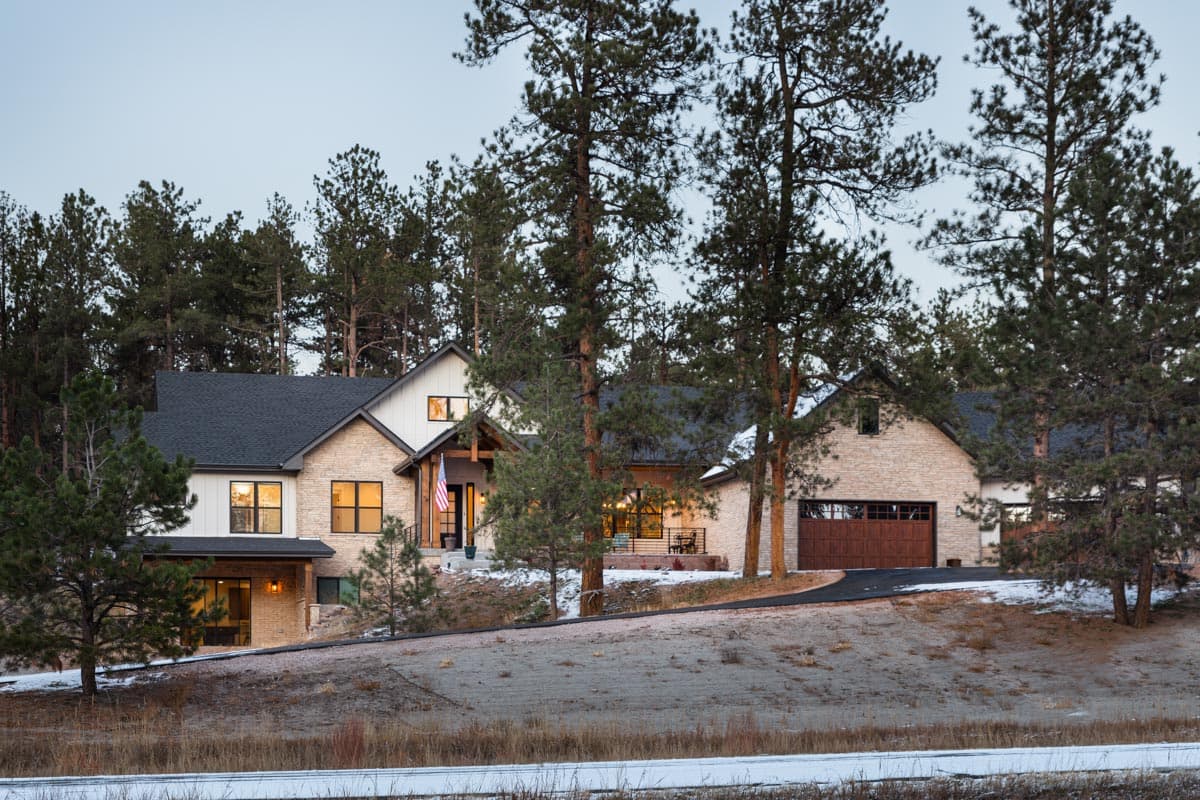 House plan exterior: Modern Farmhouse style, two stories, stone and board-and-batten siding, covered entry, and attached garage.