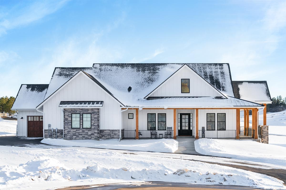 House plan exterior. Modern Farmhouse style with two stories, gabled roof, covered porch, and attached garage. Stone accents on the facade.