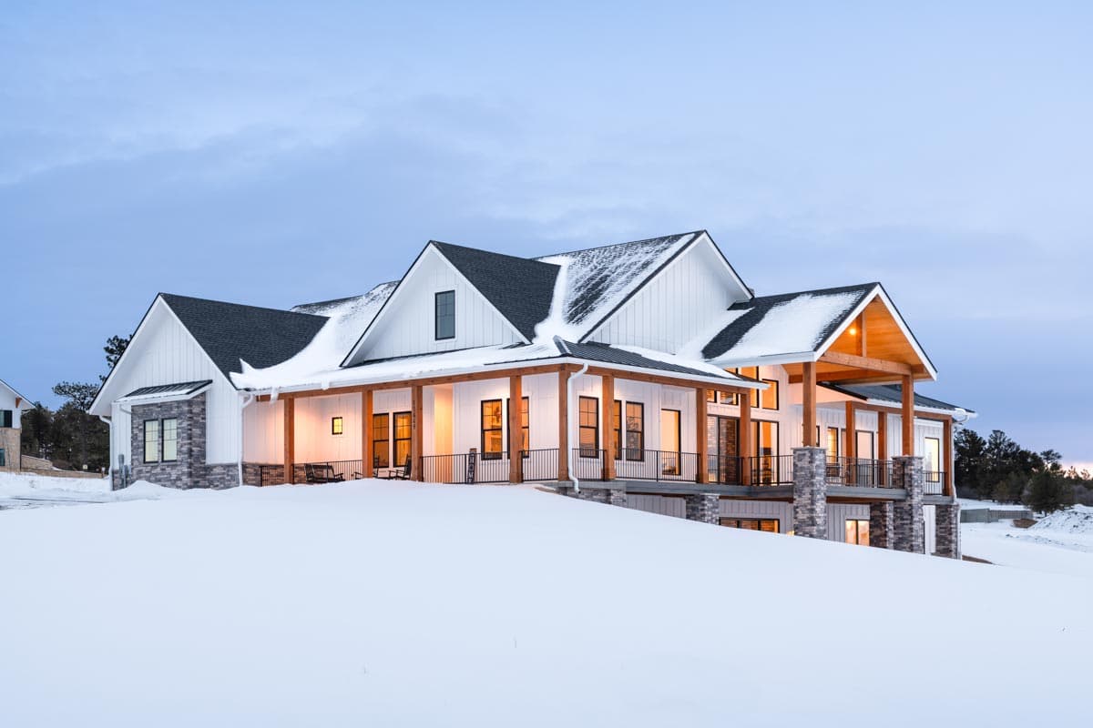 House plan exterior: Modern Farmhouse style, two stories, wrap-around porch, gabled rooflines, and stone accents.