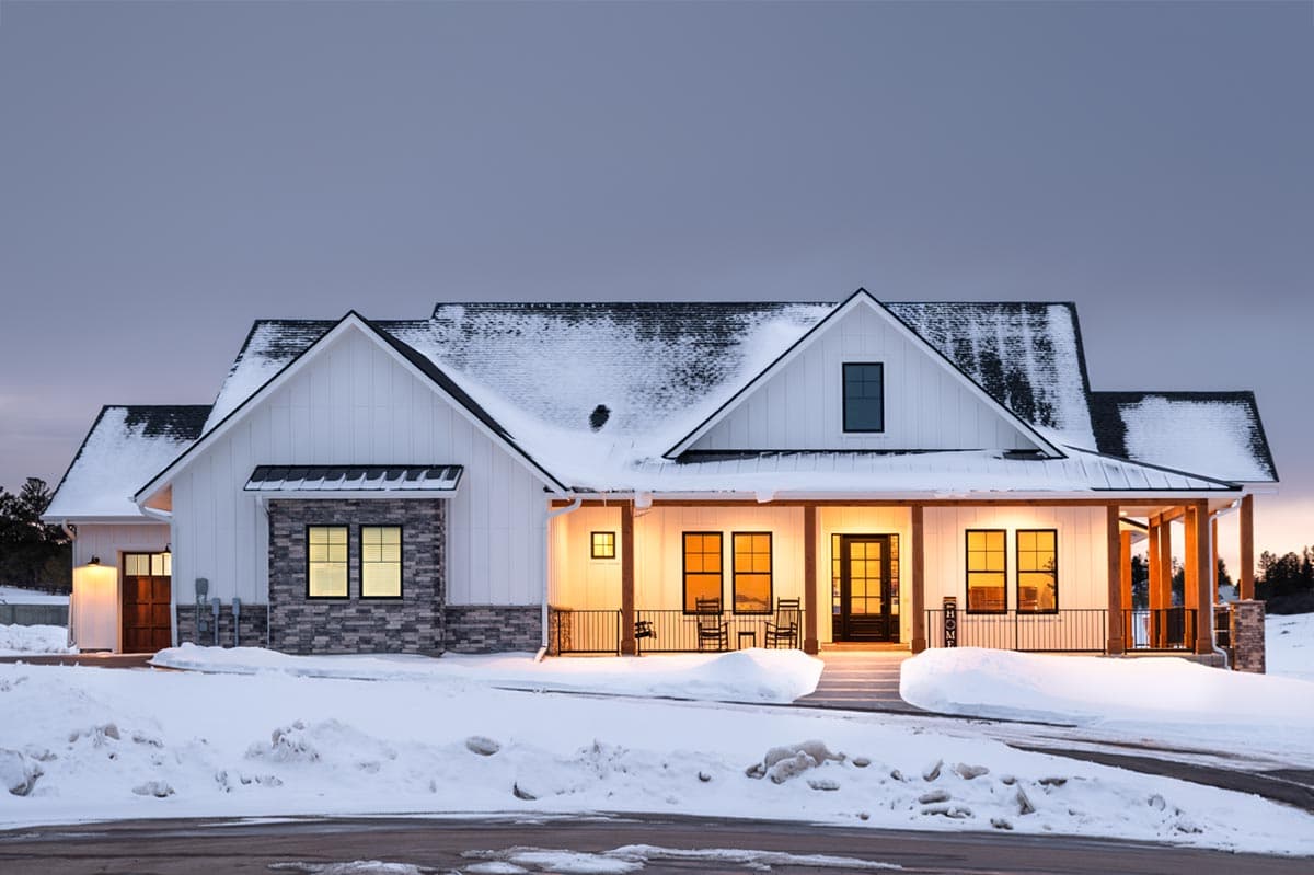 Modern Farmhouse style house plan exterior with a covered front porch, white board and batten siding, and stone accents.