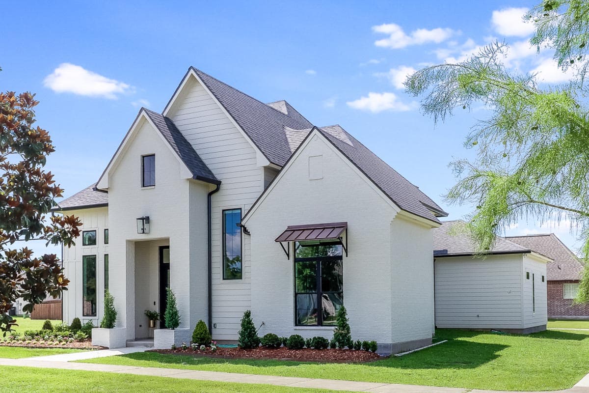 Modern Farmhouse house plan exterior with white brick and siding, multiple gables, and dark-framed windows.