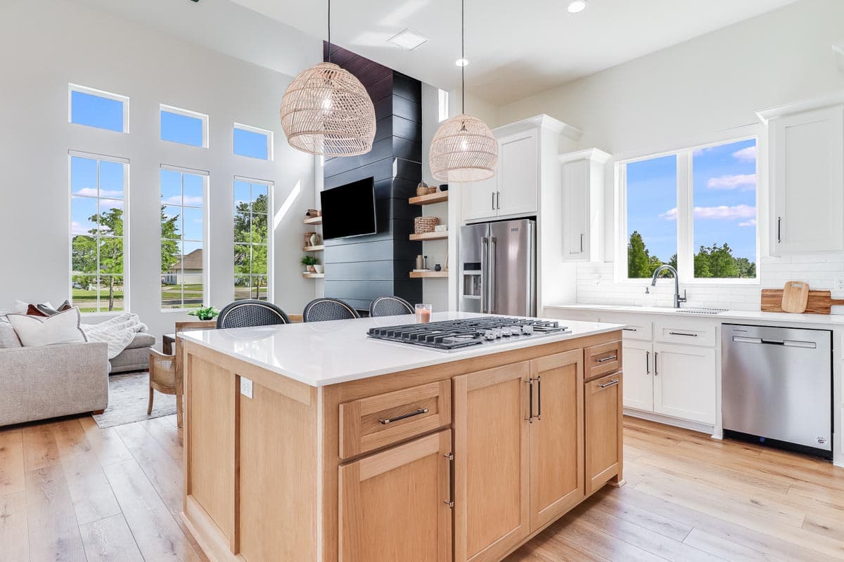 Open-concept kitchen and great room with island, gas range, vaulted ceiling, and floor-to-ceiling windows.