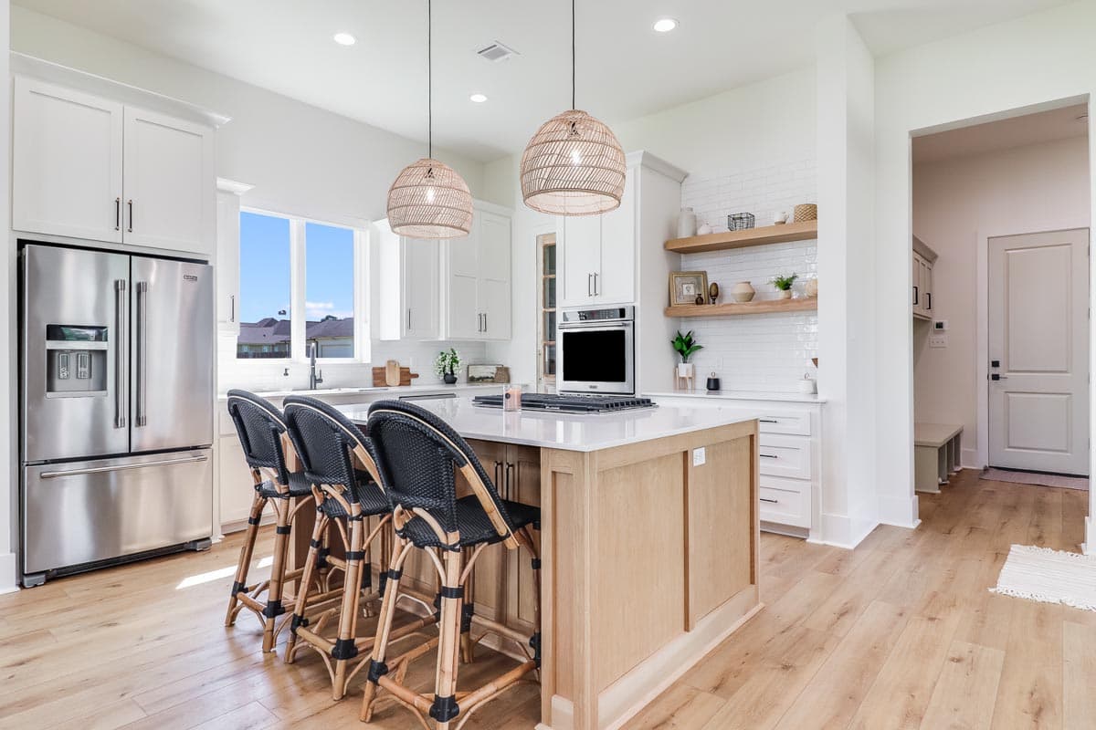 Modern kitchen with island, white cabinetry, stainless steel appliances, subway tile backsplash, and natural wood finishes.