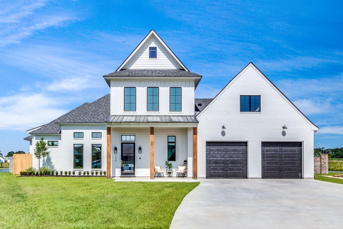 House plan exterior. Two-story Modern Farmhouse with gables, a covered porch with wood columns, and a two-car garage.