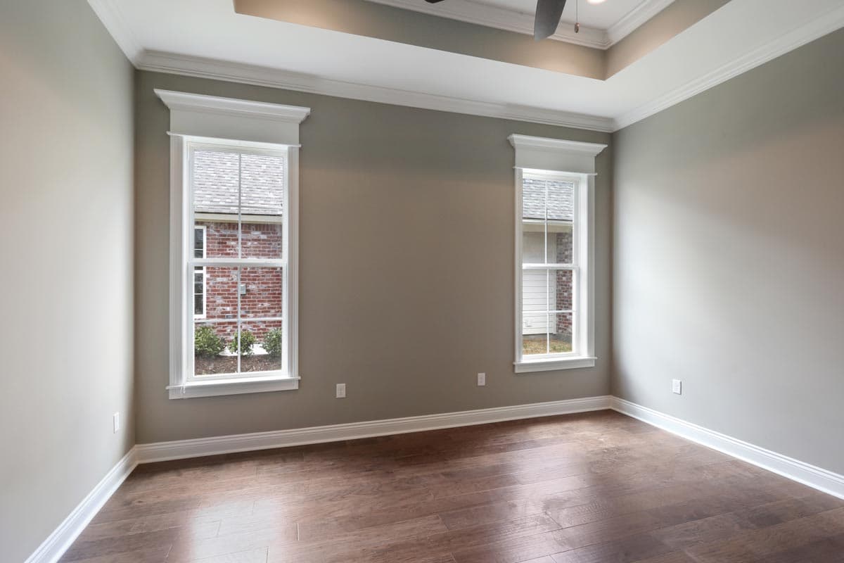 Interior view of a room with two tall, narrow windows, crown molding, and a coffered ceiling.