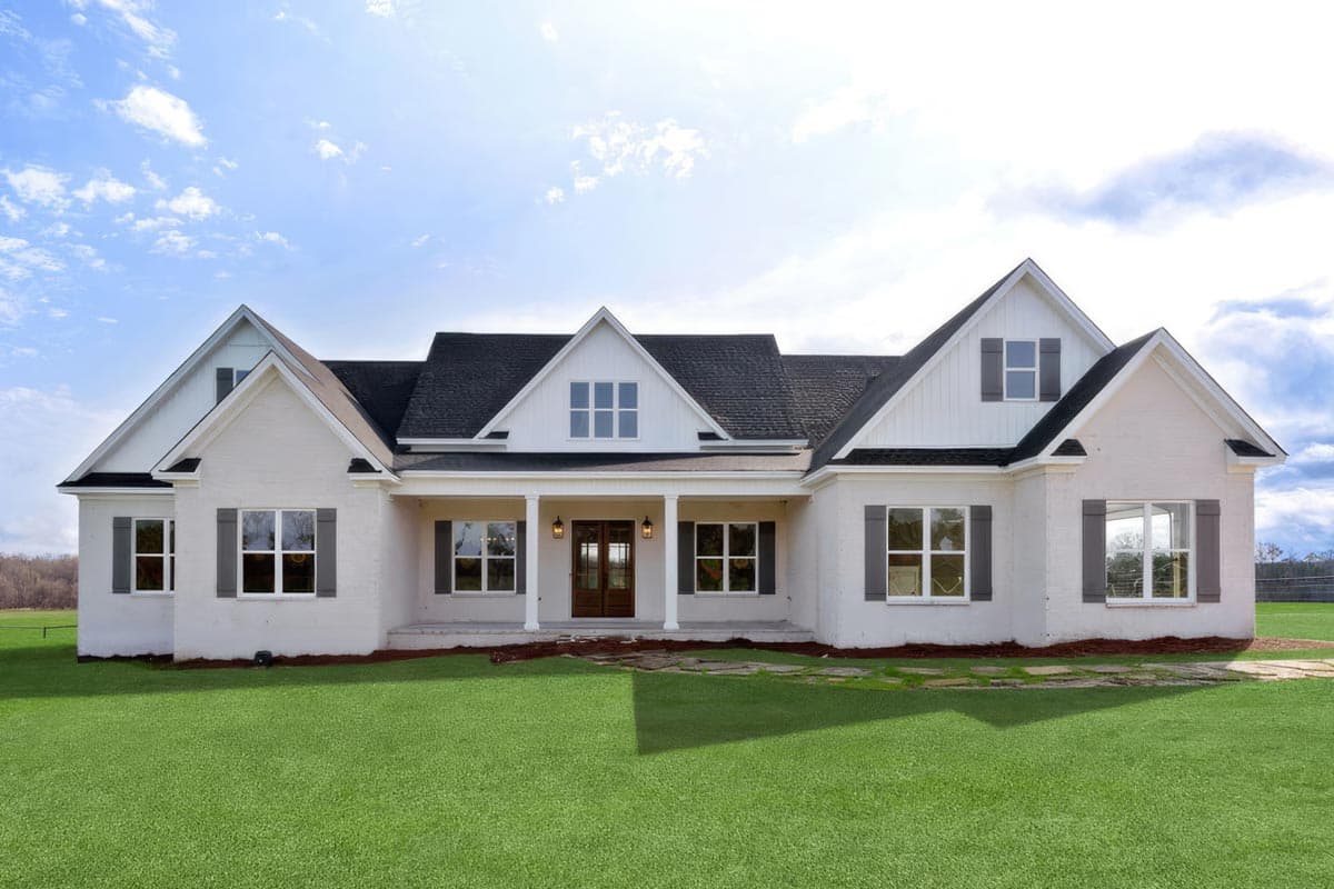 House plan exterior. Two-story, farmhouse-style home with gabled roof, dormers, and front porch with columns. Features include dark shutters.