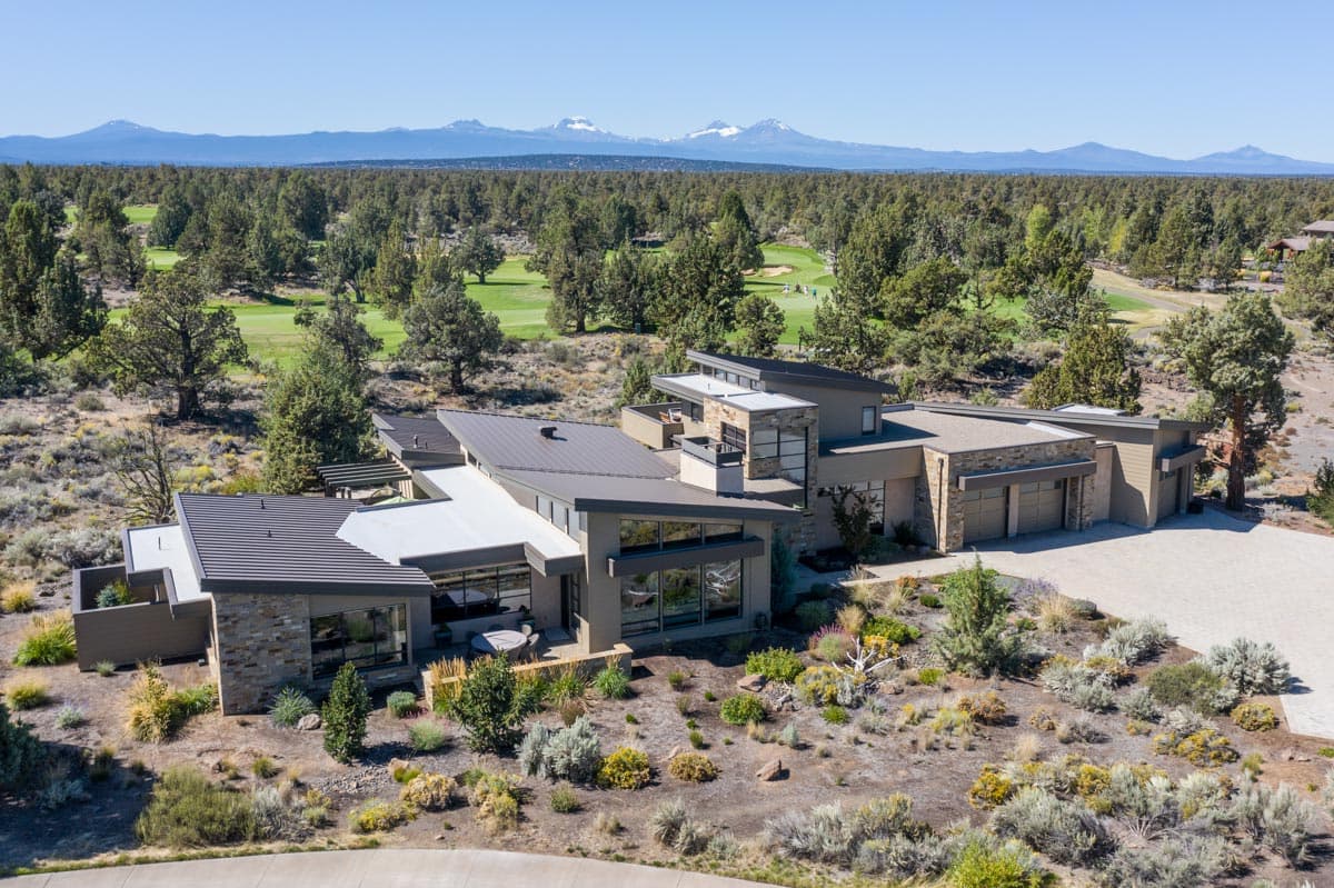 Modern house plan exterior with flat rooflines, stone accents, multi-level design, and a three-car garage.