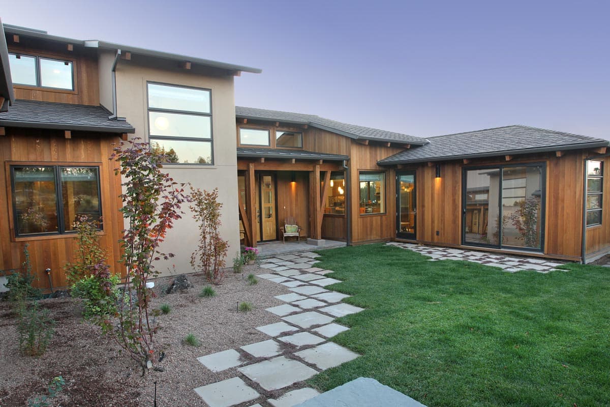 Modern house plan exterior featuring wood siding, stucco, large windows, and a covered entryway with exposed beams.