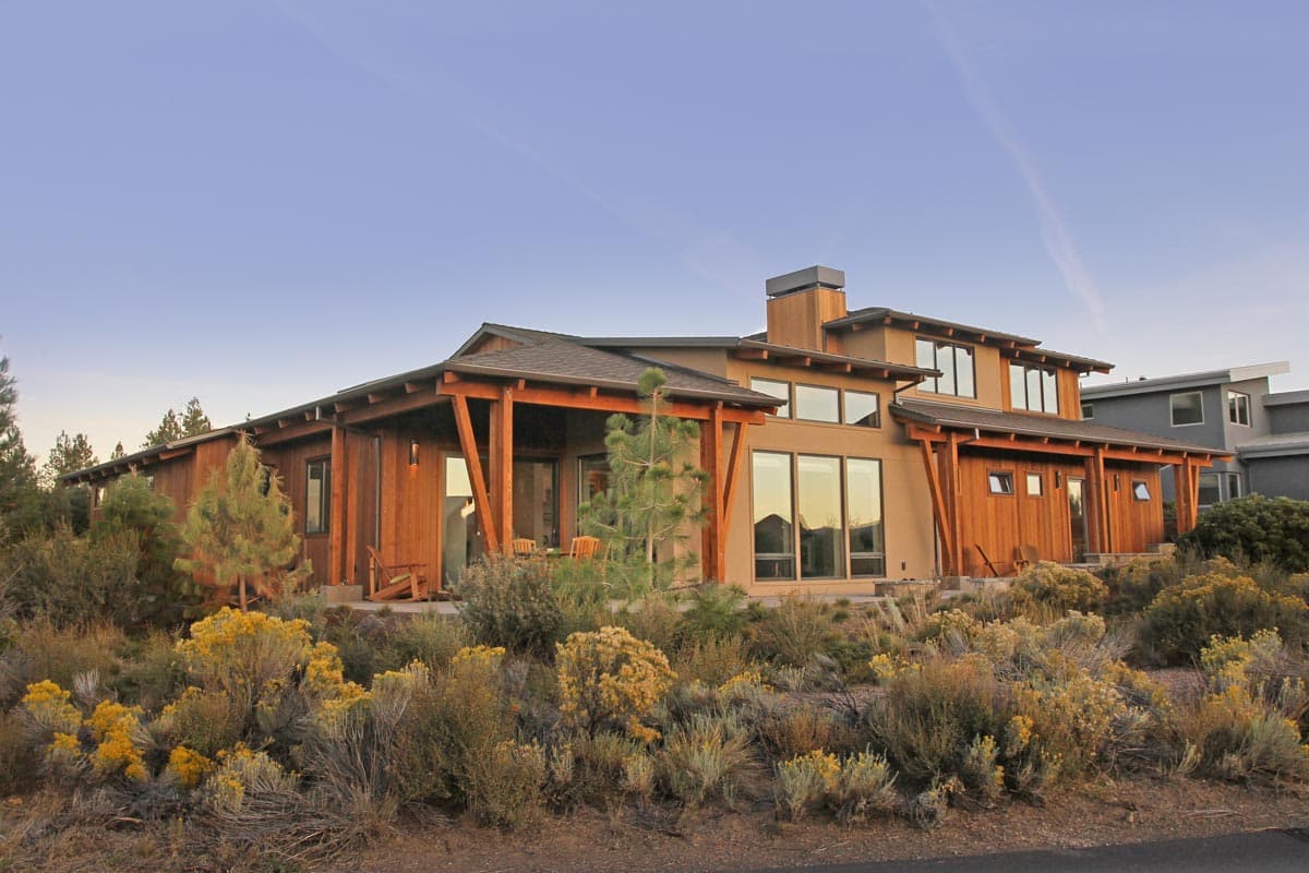 Modern house plan exterior with wood siding, large windows, covered porch, and multiple gables.