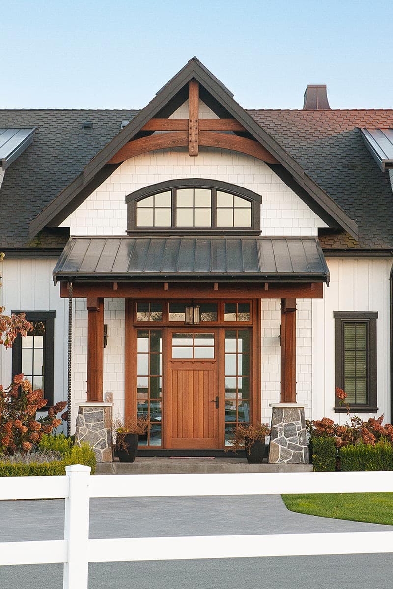 House plan exterior: Modern Farmhouse with wood entry, stone pillars, gable dormer and arched window.
