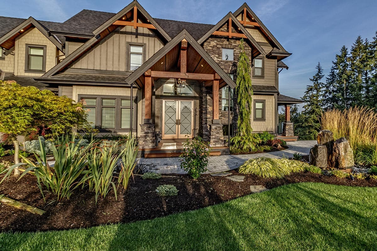 House plan exterior: Craftsman style, multiple gables with exposed wood beams, stone and wood siding, covered entry with double doors.