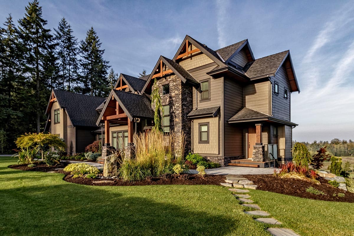 House plan exterior: Two-story home with prominent gables, stone accents, deep eaves, and covered porch.