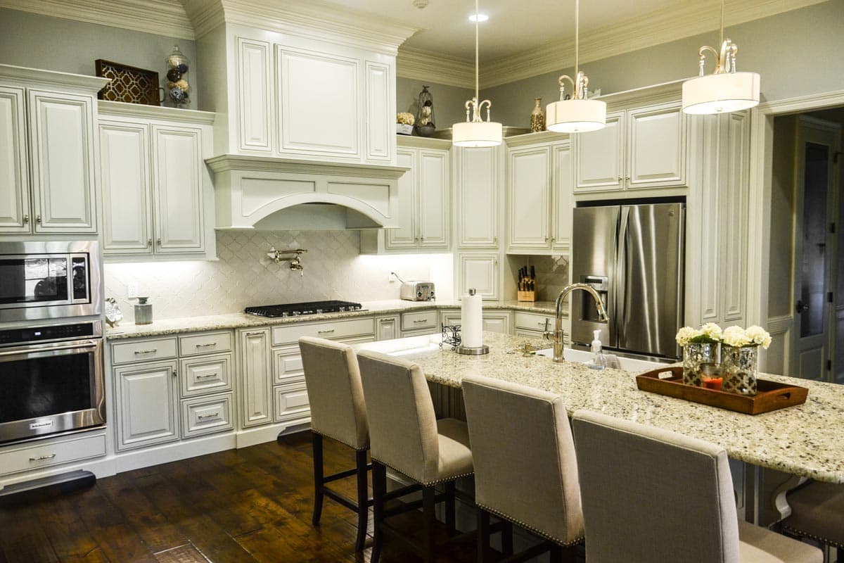 Kitchen interior with white inset cabinetry, granite countertops, stainless steel appliances, and island with seating.