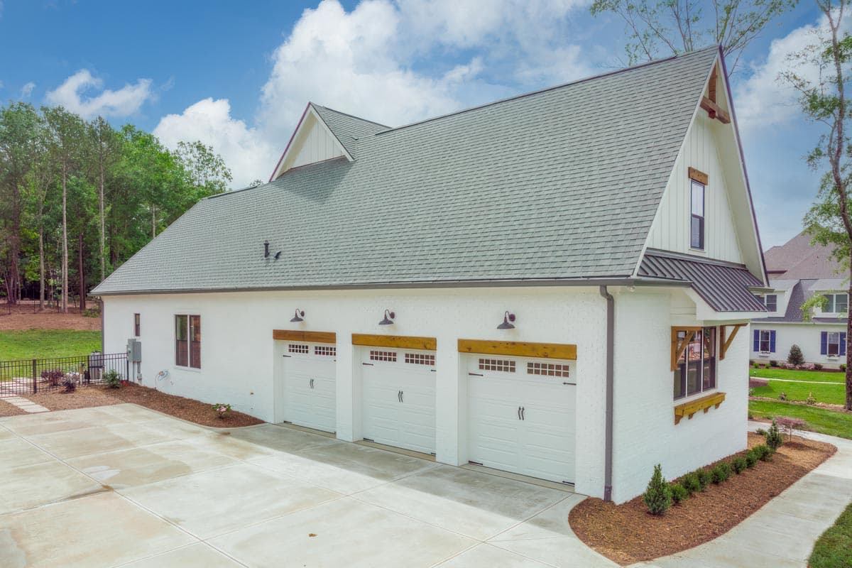 Modern Farmhouse house plan exterior with three garage doors, white brick, wood accents, and gable dormers.
