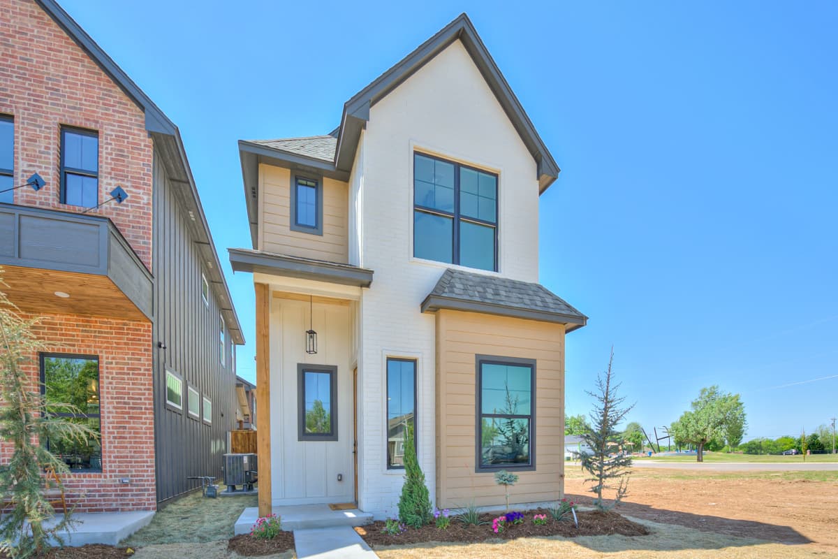 House plan exterior: two-story Modern Farmhouse with white brick, tan siding, gabled roof, and covered front porch.