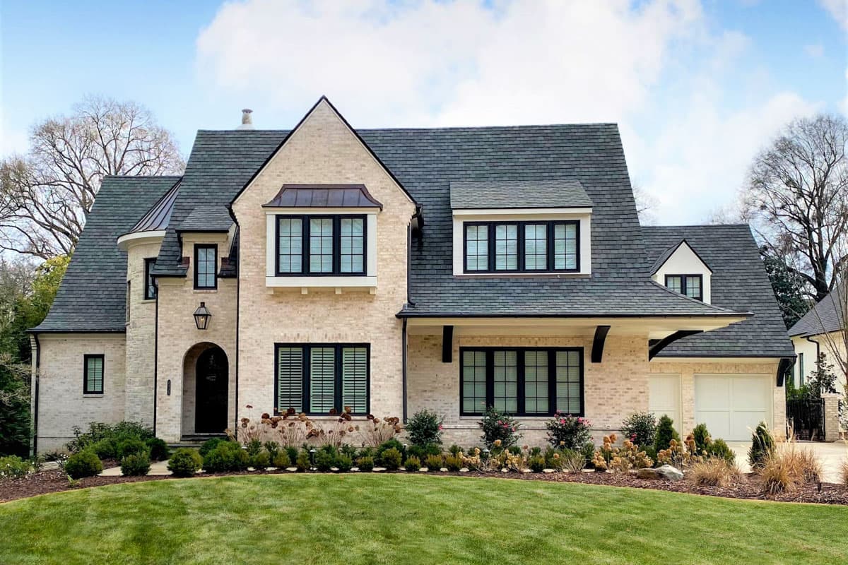 House plan exterior with two stories. Features include a prominent roofline, arched entryway, and multiple gables.  Attached garage on the right.