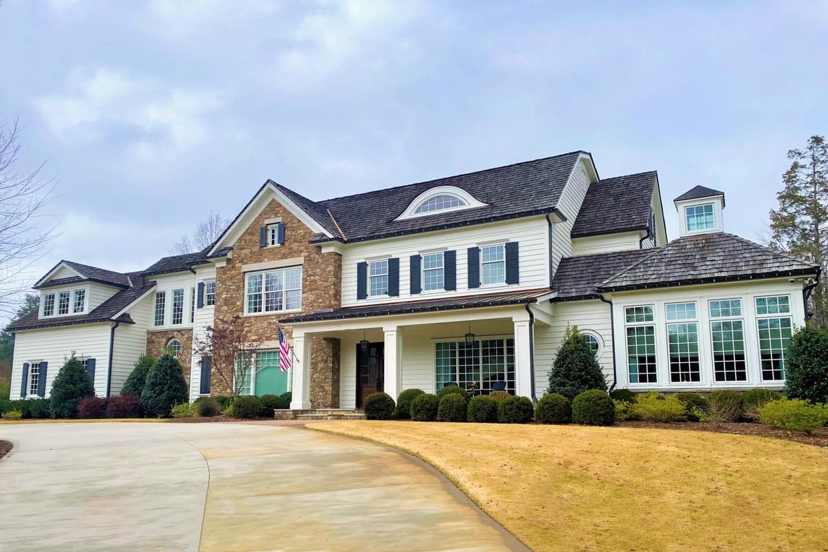 House plan exterior featuring a two-story traditional style home with a portico, gables, and multi-paned windows.