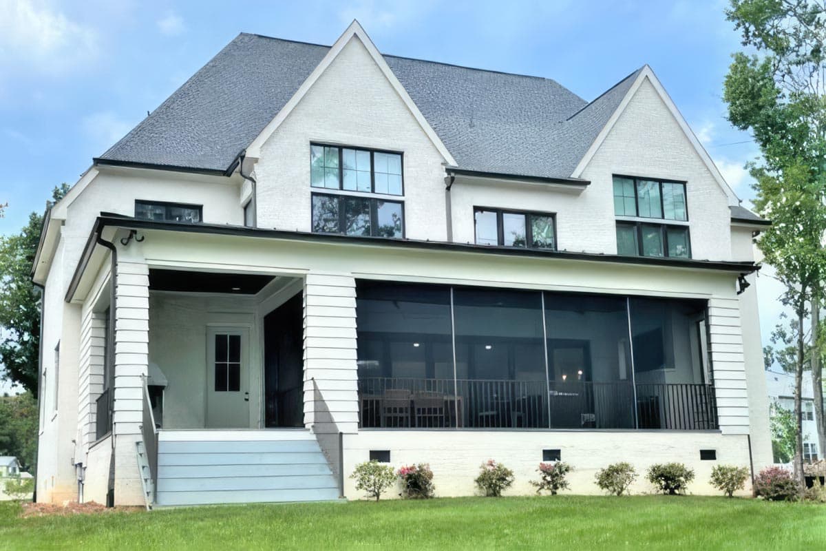 House plan exterior: two-story white brick house with gables, a covered porch, and a screened-in patio.
