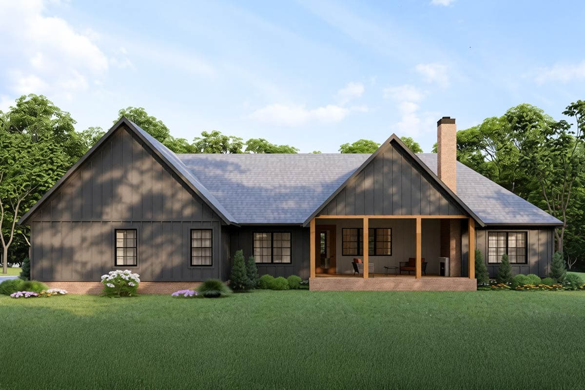 A modern farmhouse with dark gray siding, a covered porch, and a brick chimney is set on a lush green lawn, surrounded by trees.