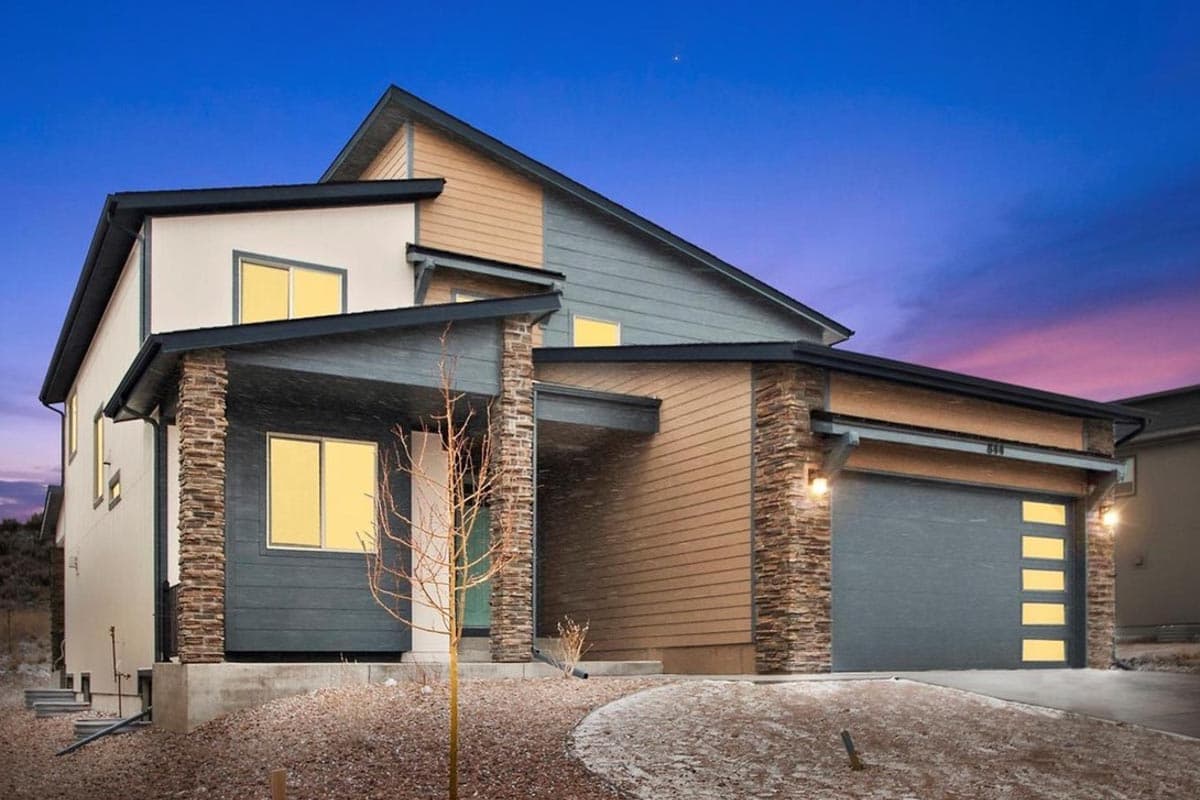 Modern house plan exterior with stone accents, two stories, gabled rooflines, and attached garage with modern door.