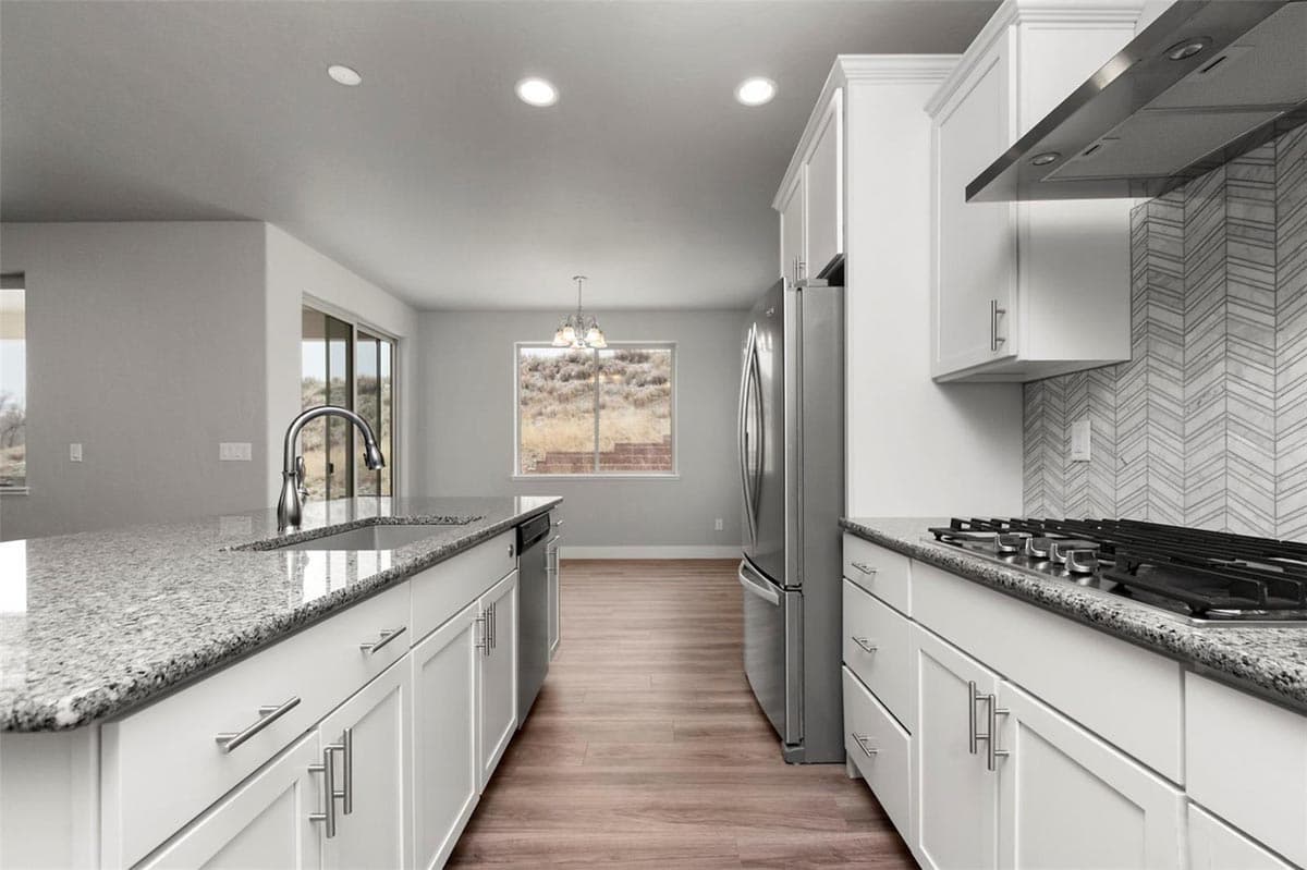 Modern kitchen with white cabinets, granite countertops, stainless steel appliances, and a herringbone tile backsplash.