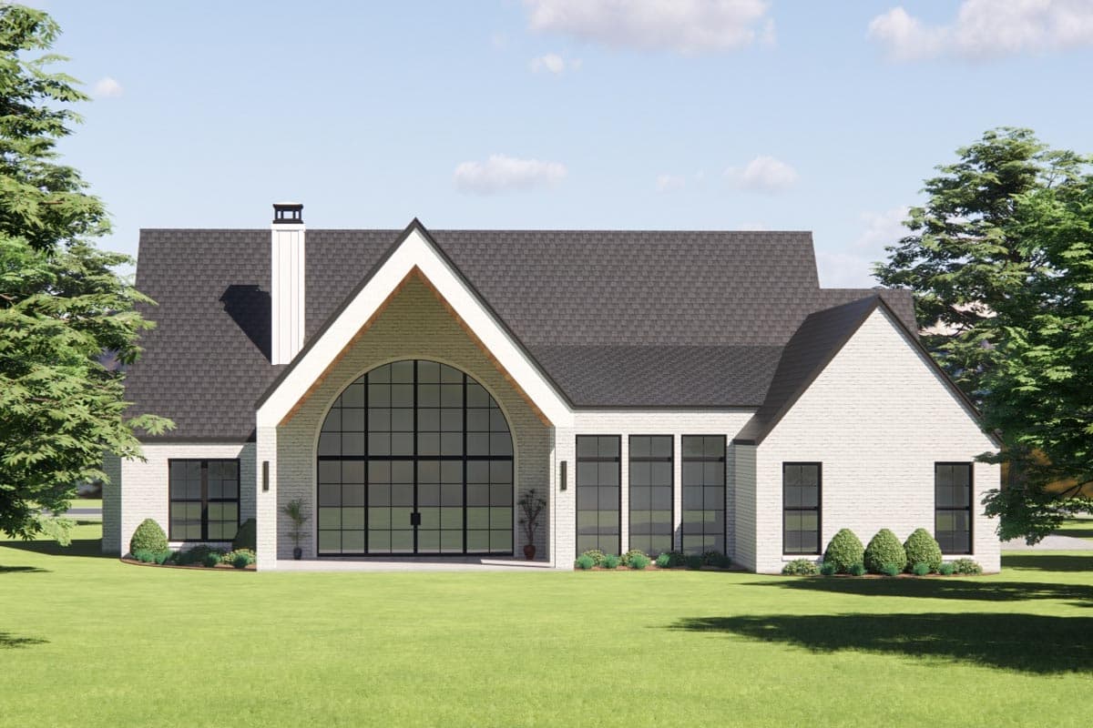 House plan exterior with large arched window, gabled rooflines, white brick, and a prominent chimney.
