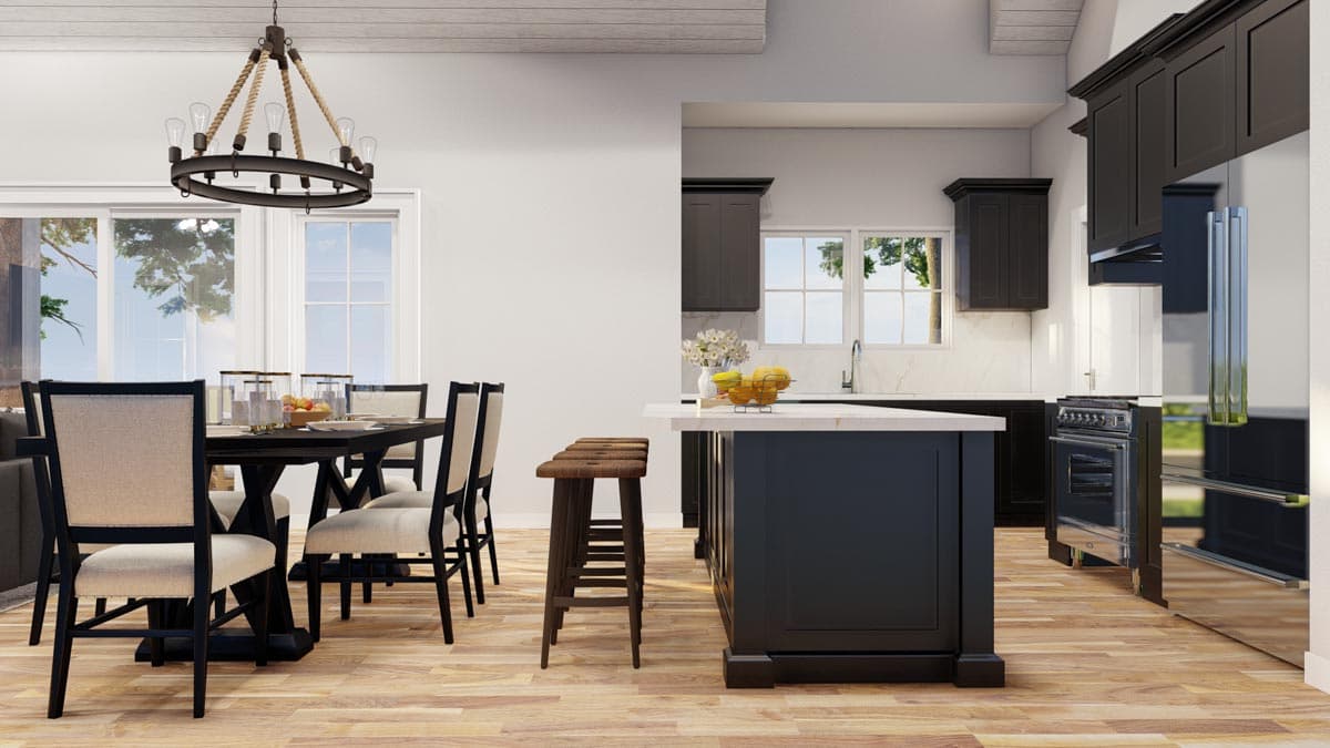 Dining area with dark wood table and chairs adjacent to kitchen with island, dark cabinets, and stainless steel appliances.