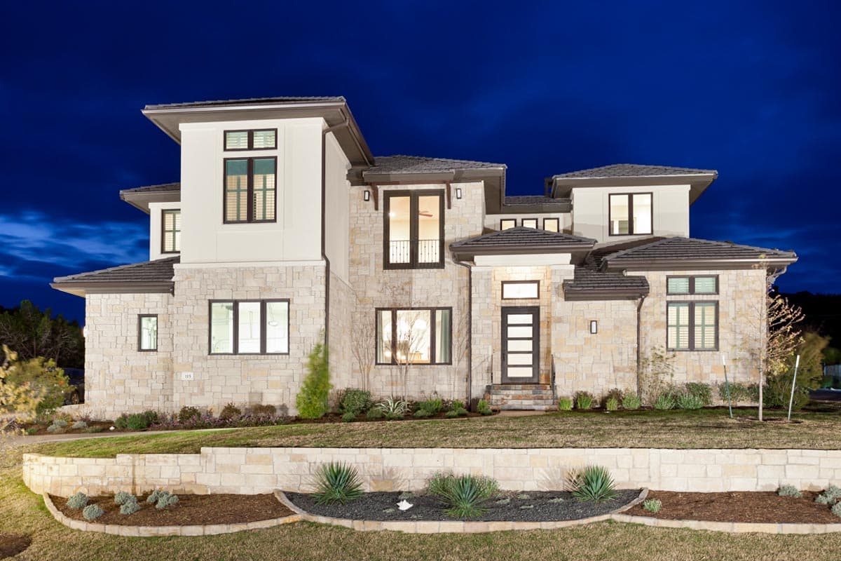 House plan exterior. Two-story contemporary home with stone veneer. Features include a flat roof, multiple gables, and a modern front entry door.