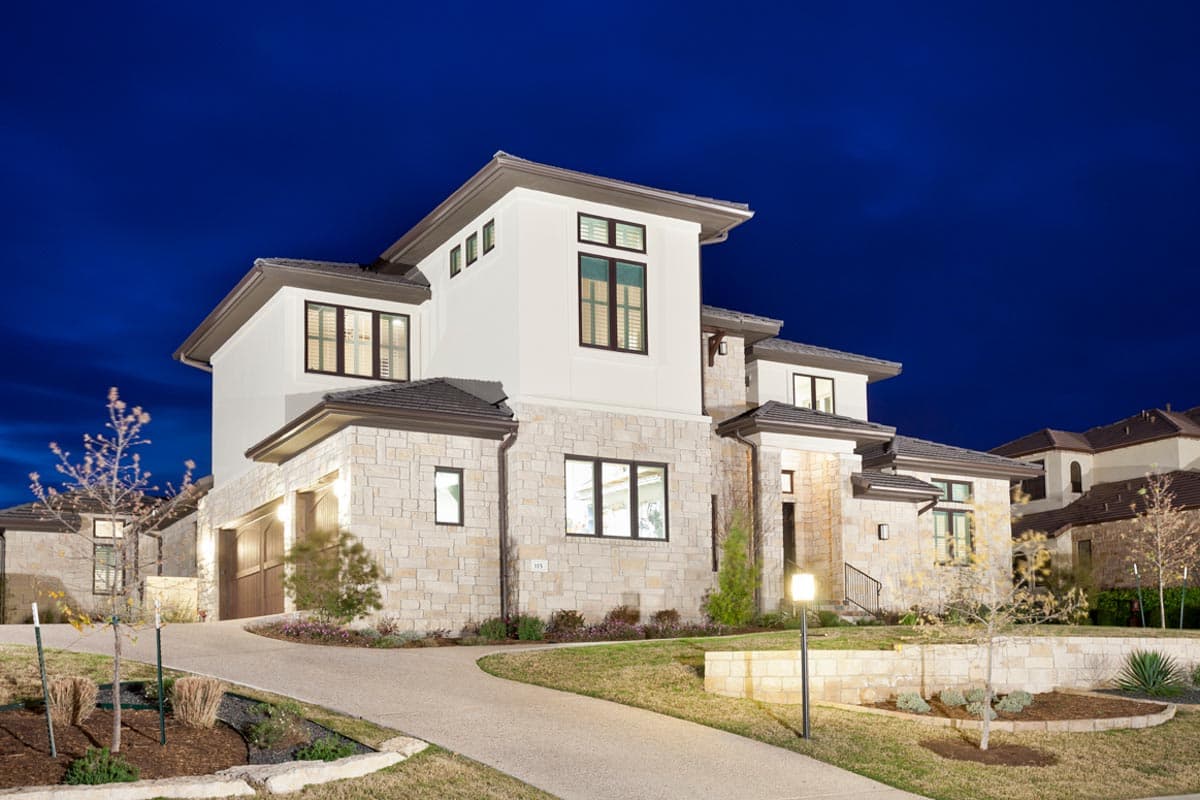 Modern house plan exterior with stone facade, stucco finish, multiple rooflines, and a three-car garage.