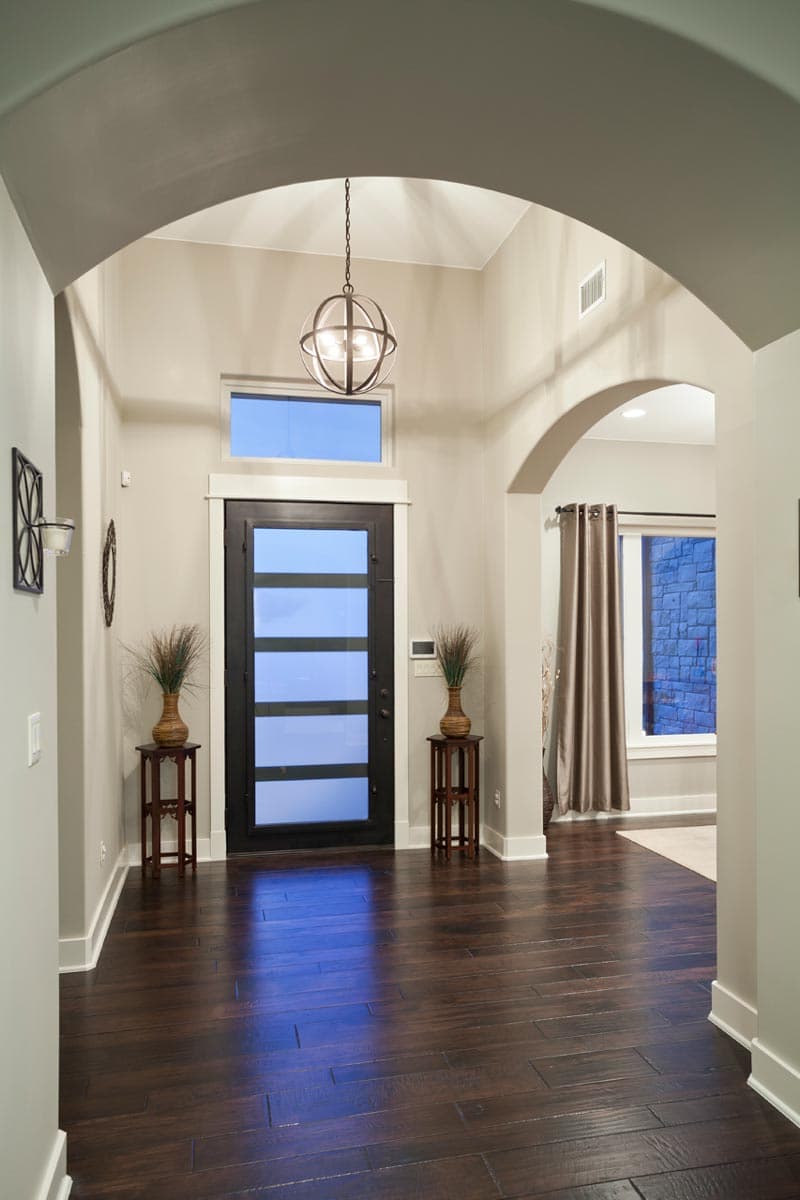 Entrance hall with vaulted ceiling, contemporary door with glass panels, and arched interior doorways.