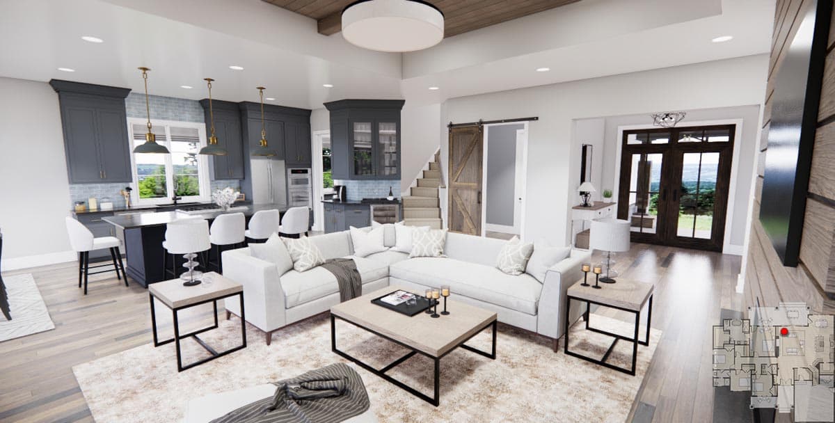 Open-concept living and kitchen area with large sectional, island with seating, and a sliding barn door leading to stairs.