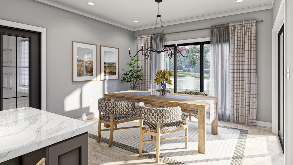 Dining area with wood table, patterned chairs, and large window overlooking a white picket fence.
