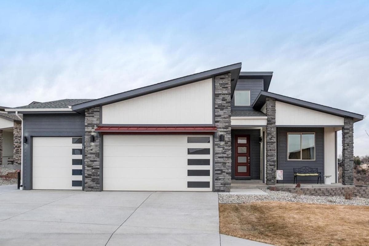 House plan exterior. Modern style, single story. Features include asymmetrical roofline, stone accents, and a front-facing garage.
