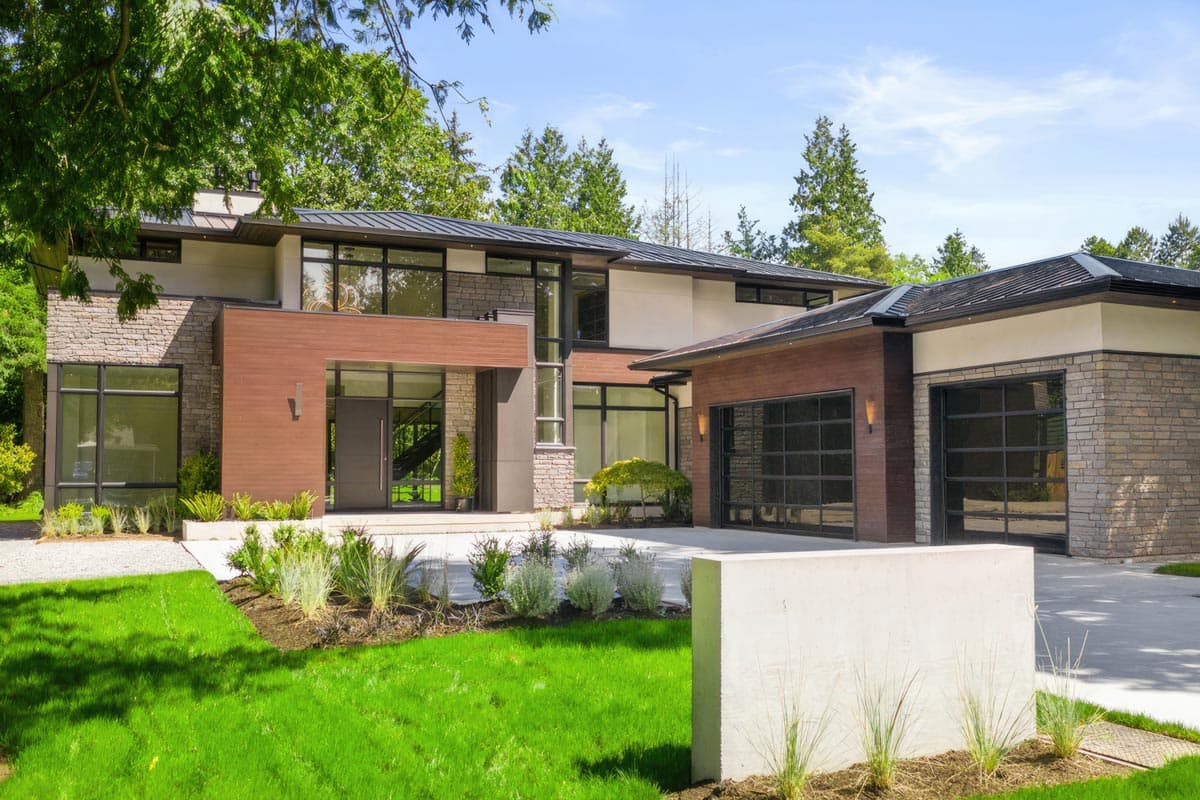 Modern house plan exterior with stone and wood siding, flat rooflines, multiple gables, and two glass garage doors.
