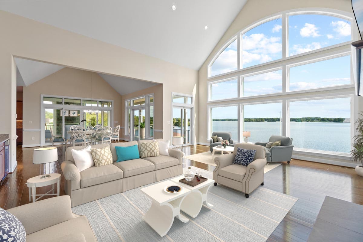 Great room with vaulted ceiling and wall of windows overlooking water. Open to dining area.