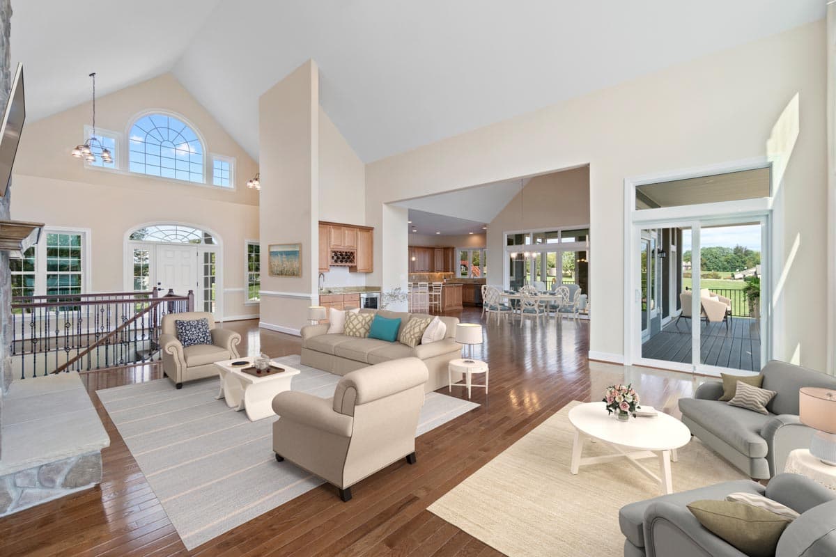 Open concept great room with vaulted ceiling, fireplace, and access to dining room, kitchen, and deck.